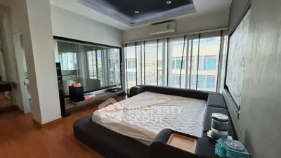 Spacious bedroom with large windows and modern design, featuring a comfortable bed and ample natural light.