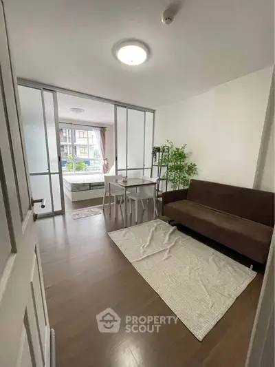 Modern studio apartment with sliding glass doors, cozy living area, and natural light.