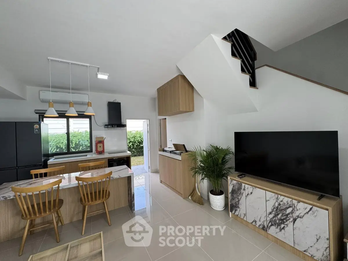 Modern open-plan living room with stylish kitchen and sleek staircase