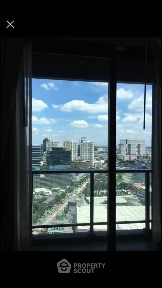 Stunning cityscape view from high-rise apartment window with clear blue skies.