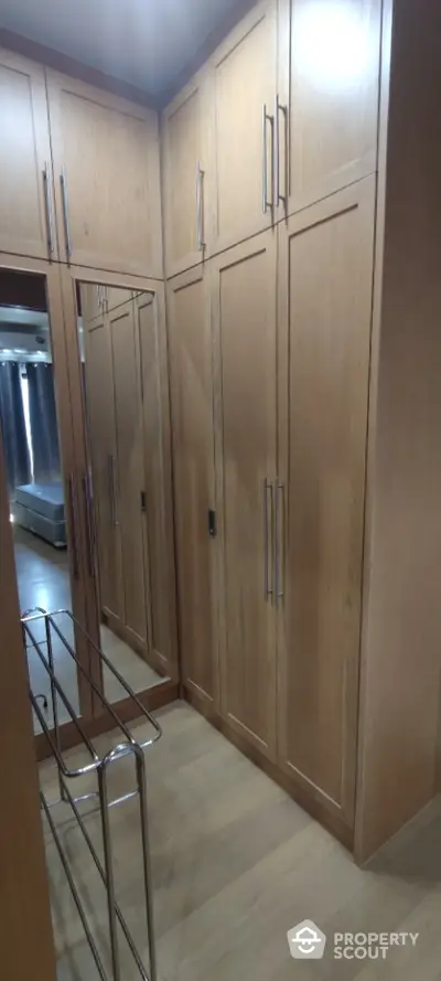 Spacious walk-in closet with wooden cabinetry and mirrored doors in modern home.