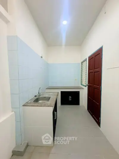 Compact kitchen with tiled walls and modern sink in a cozy apartment