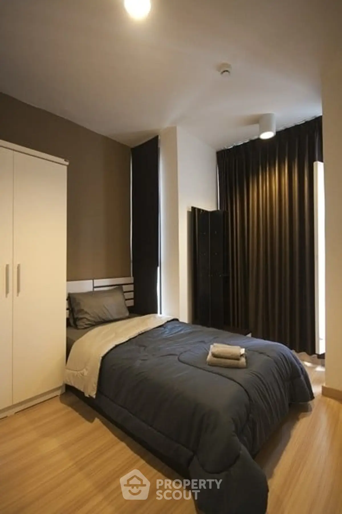 Cozy bedroom with modern decor and ample natural light, featuring a comfortable bed and stylish wardrobe.
