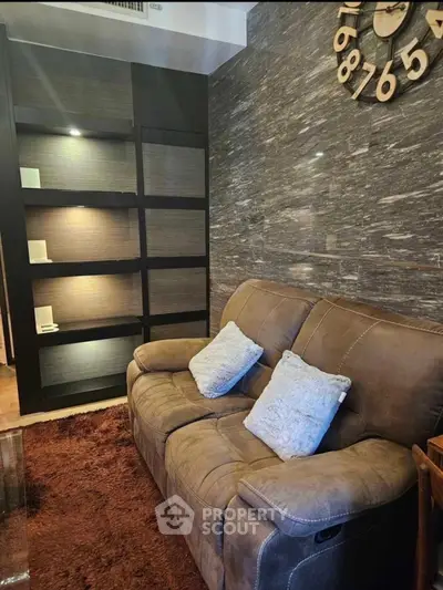 Cozy living room with plush sofa and modern wall clock, perfect for relaxation.