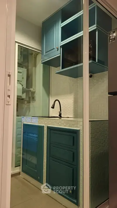Modern compact kitchen with blue cabinets and sleek black faucet
