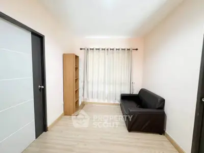 Minimalist living room with sleek black sofa and wooden bookshelf
