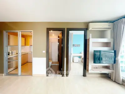 Modern apartment interior with open kitchen, bathroom, and living area featuring air conditioning and TV.