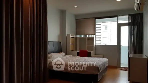 Spacious bedroom with modern decor and balcony access in a stylish apartment.