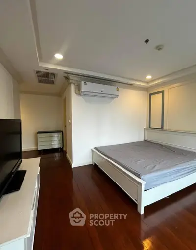 Spacious bedroom with wooden flooring and modern air conditioning unit
