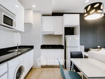 Modern kitchen with sleek white cabinets, black countertops, and integrated appliances in a stylish apartment.