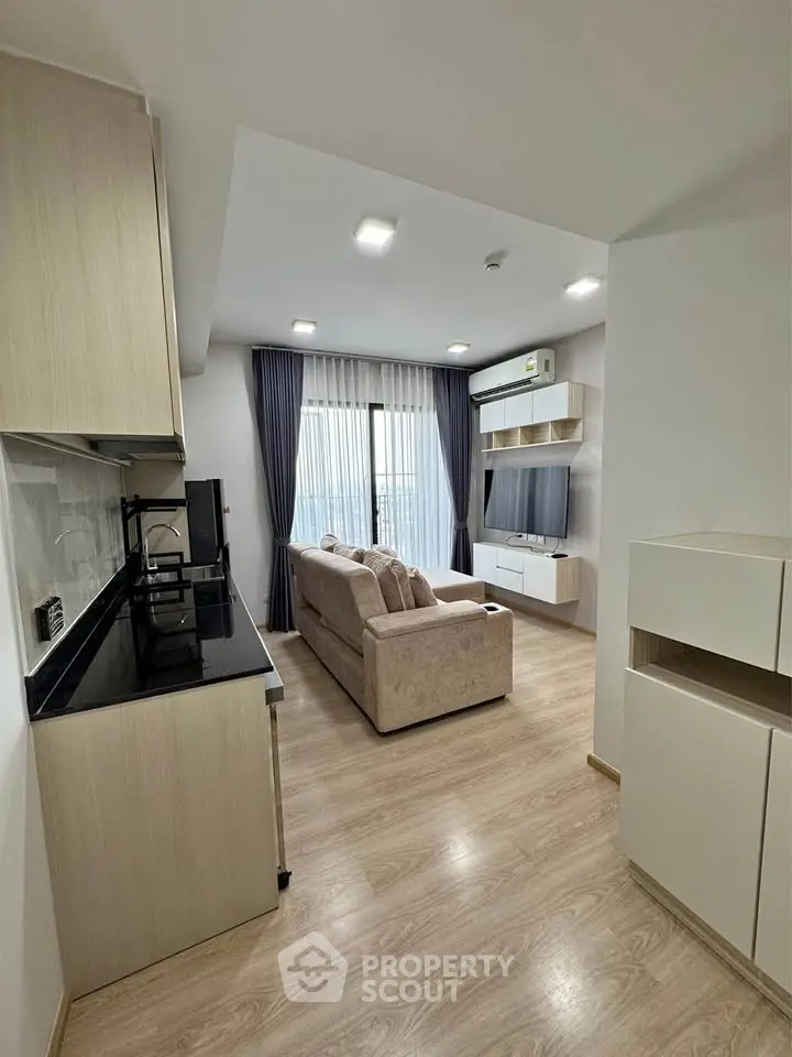 Modern living room with open kitchen, featuring sleek design and natural light.