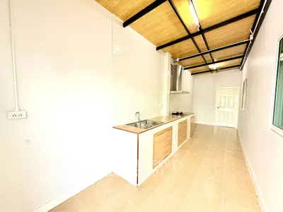 Modern kitchen with sleek design and open layout, featuring wooden ceiling and tiled floor.
