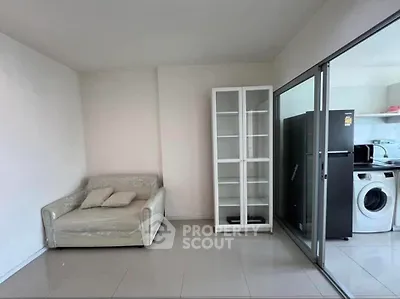 Modern living room with glass cabinet and adjacent laundry area featuring washing machine and fridge.