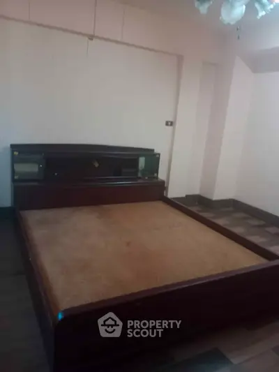 Spacious bedroom with wooden flooring and a large bed frame, ideal for cozy living.