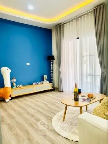 Stylish living room with blue accent wall, modern decor, and large window for natural light.