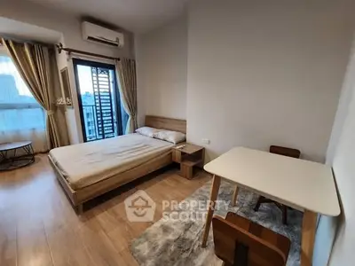 Modern bedroom with wooden flooring, cozy bed, and a small dining table near a window.