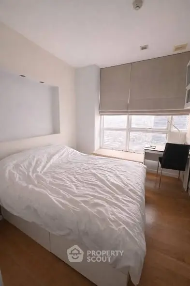 Cozy bedroom with large window and city view, featuring a comfortable bed and study desk.