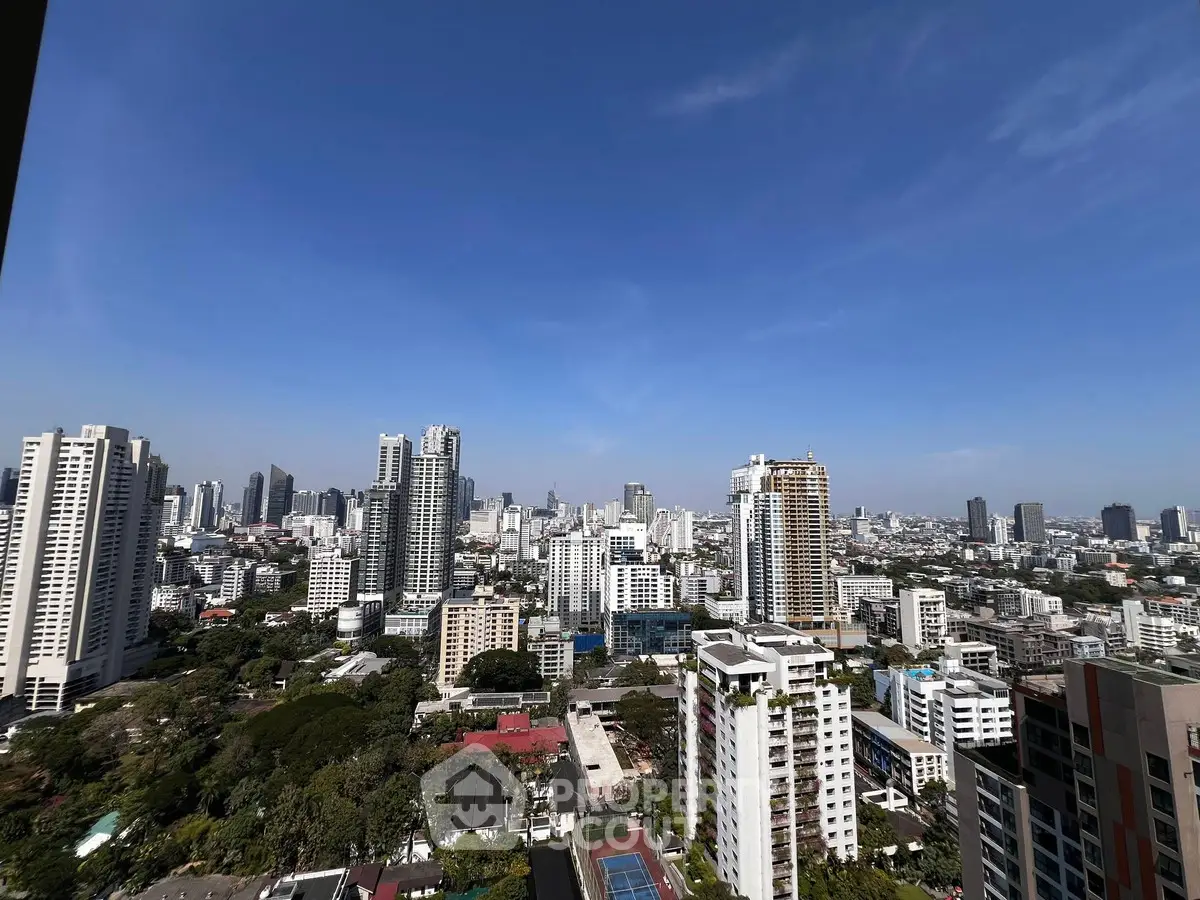 Stunning cityscape view from a high-rise building, showcasing urban skyline and clear blue sky.