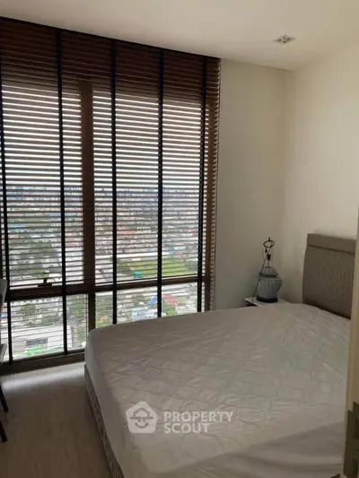Cozy bedroom with large window and city view, featuring modern blinds and comfortable bed.