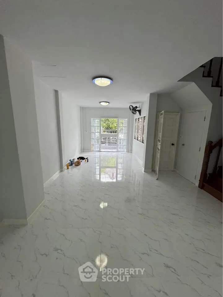 Spacious modern living room with glossy marble flooring and large windows for natural light.