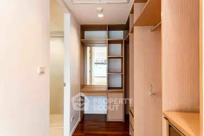 Spacious walk-in closet with wooden shelving and elegant design in modern apartment.