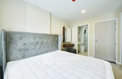 Spacious bedroom with plush headboard and ensuite bathroom in modern apartment.