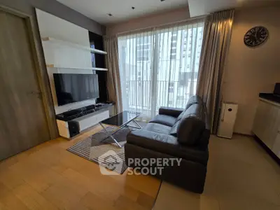 Modern living room with sleek leather sofa, large TV, and floor-to-ceiling windows offering city views.