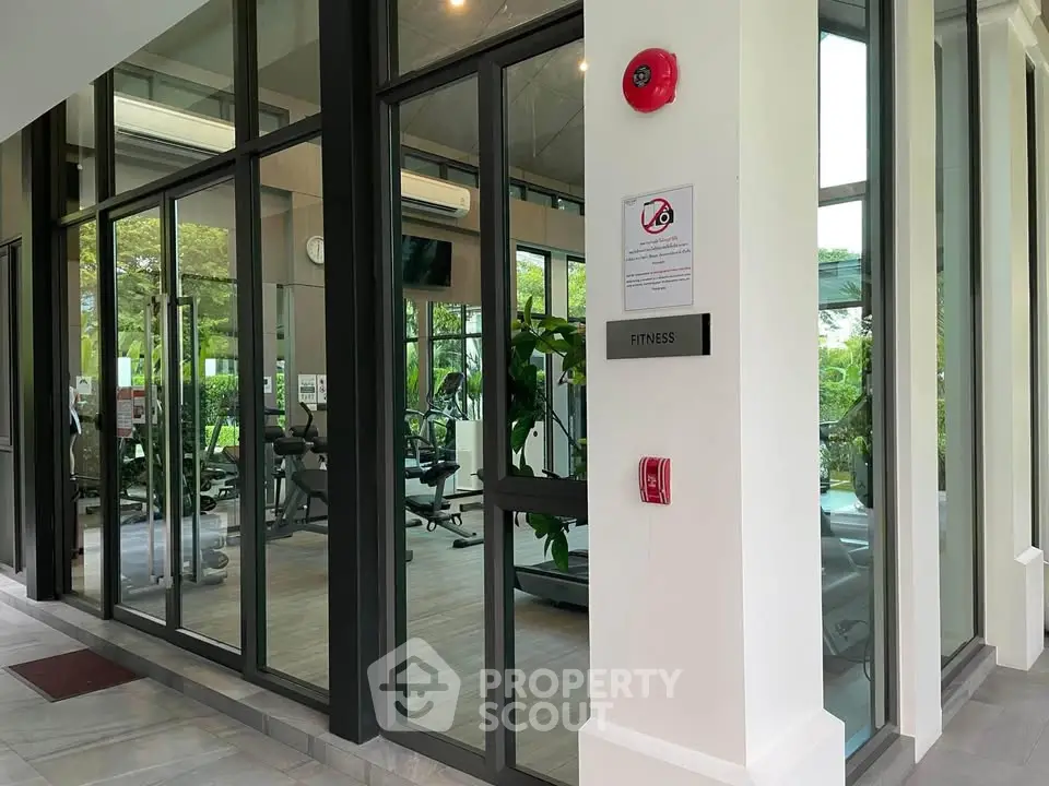 Modern fitness gym with glass walls and lush greenery view