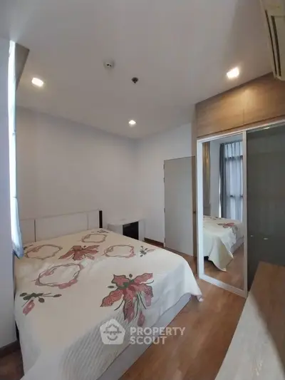 Cozy bedroom with mirrored closet and floral bedding in modern apartment.