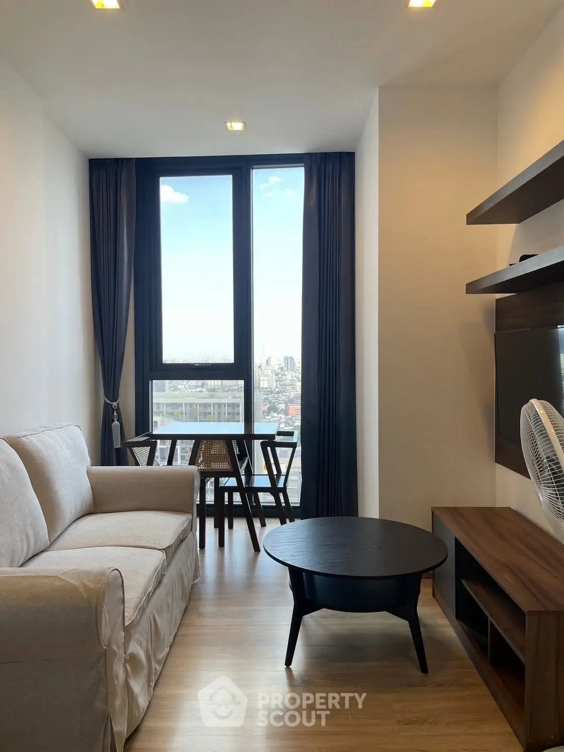 Modern living room with city view, cozy sofa, and stylish furniture in a high-rise apartment.