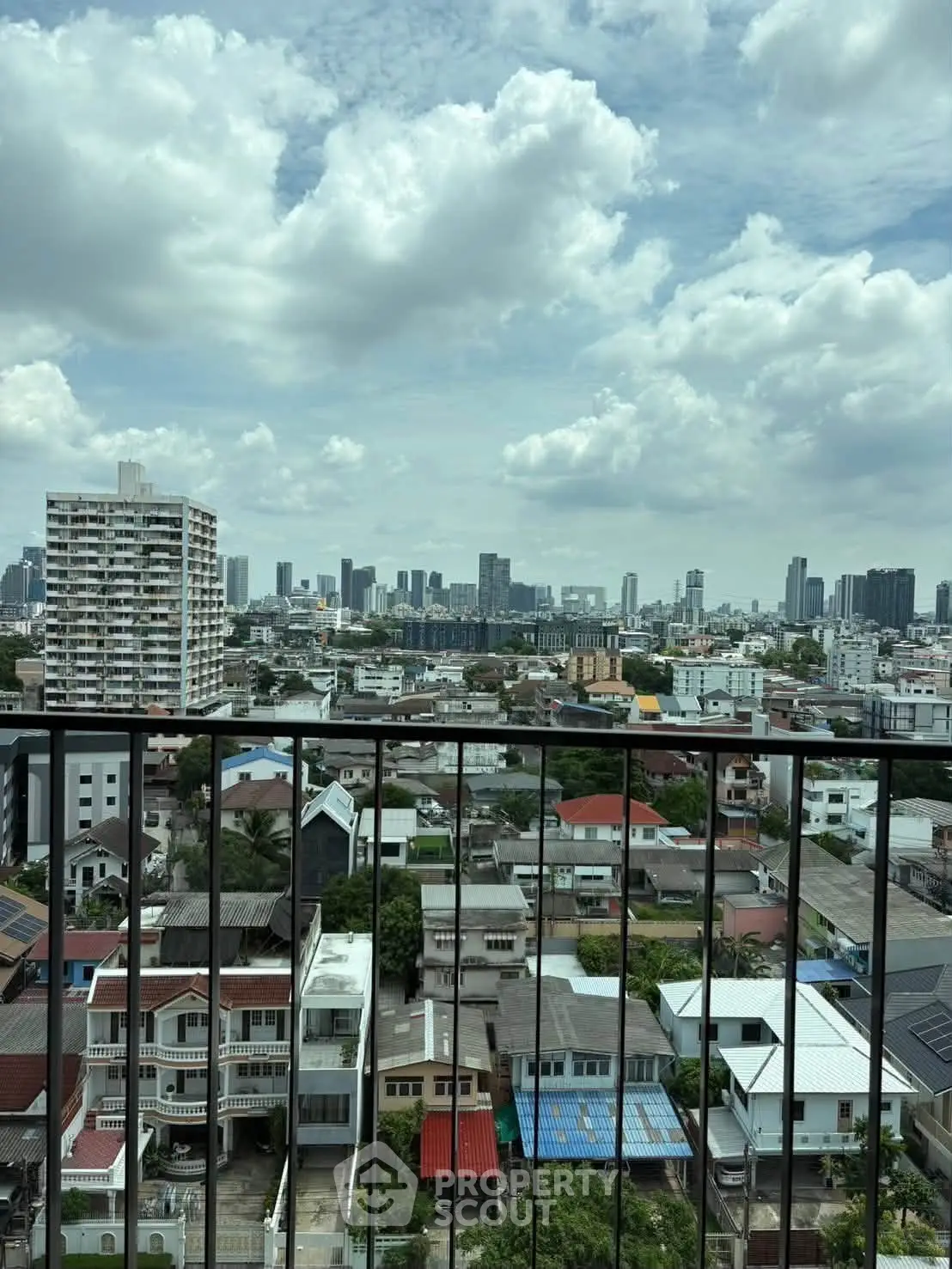 Stunning cityscape view from a high-rise balcony showcasing urban skyline and residential area.