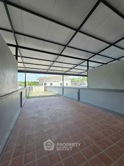 Spacious covered terrace with tiled flooring and open view, ideal for outdoor relaxation.