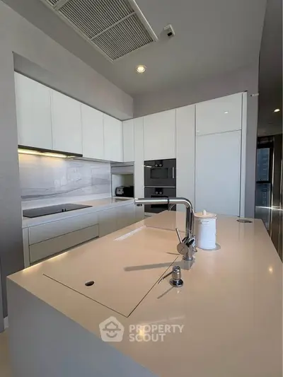Modern kitchen with sleek white cabinetry and island, featuring built-in appliances and minimalist design.