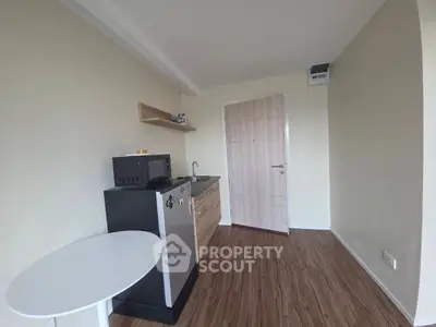 Compact kitchenette with modern appliances and wooden flooring in a cozy apartment.