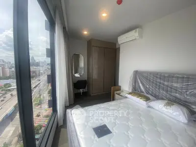 Modern bedroom with city view, featuring a large window and stylish decor.
