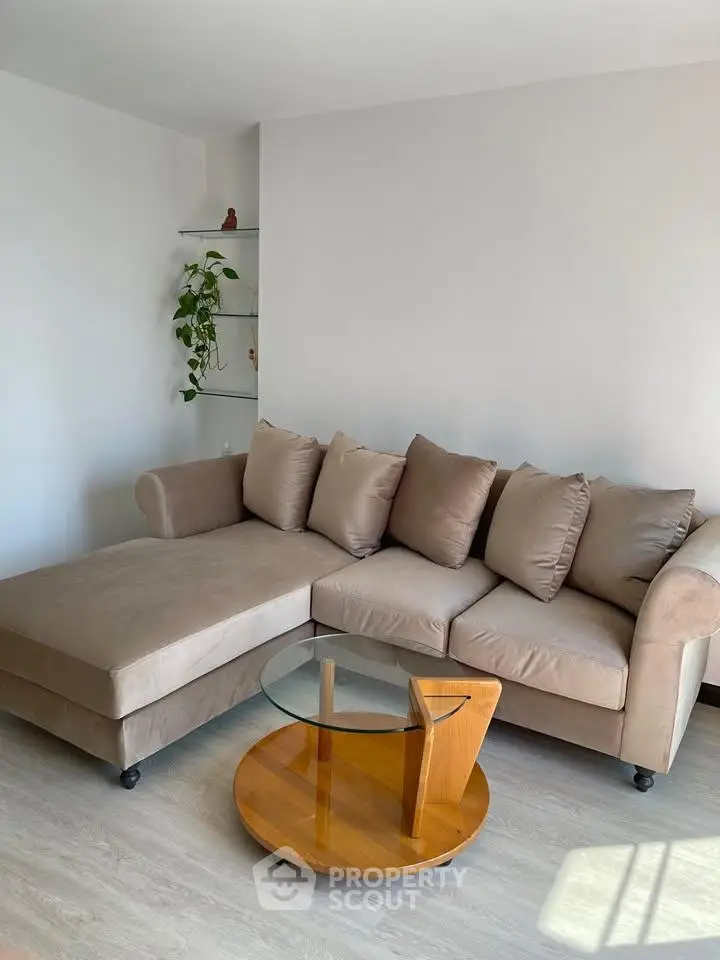 Modern living room with stylish beige sectional sofa and glass coffee table, perfect for relaxation.