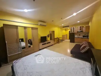 Spacious studio apartment with vibrant yellow walls and modern furnishings.