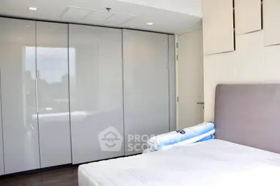 Modern bedroom with sleek wardrobe and cozy bed in bright natural light.