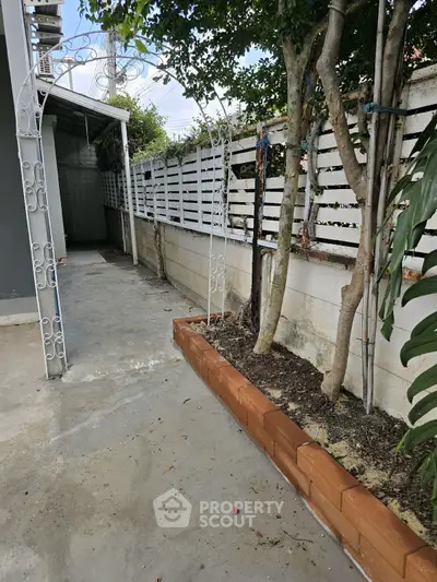 Charming garden area with brick border and decorative archway, perfect for outdoor relaxation.