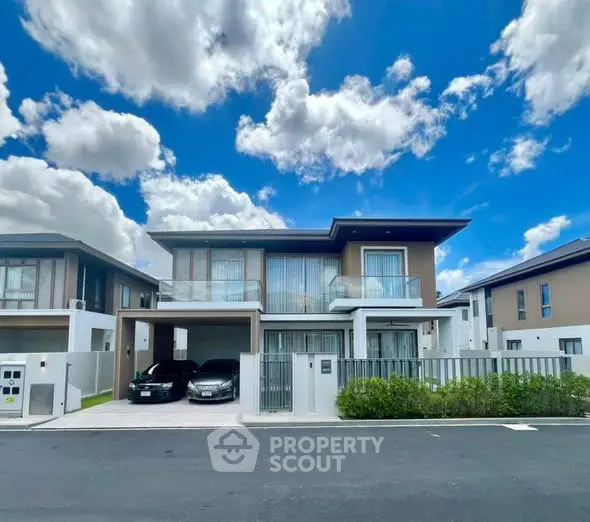 Modern two-story house with sleek design and spacious driveway under a vibrant blue sky.