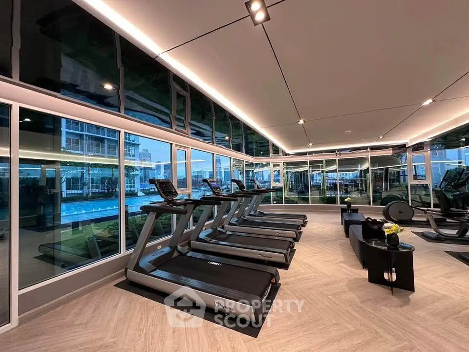 Modern gym with treadmills and pool view in luxury residential building.