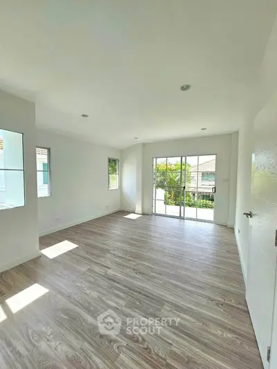 Spacious and bright living room with large windows and sliding glass doors leading to a balcony.