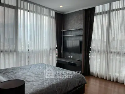 Luxurious bedroom with floor-to-ceiling windows offering stunning city views and modern decor.