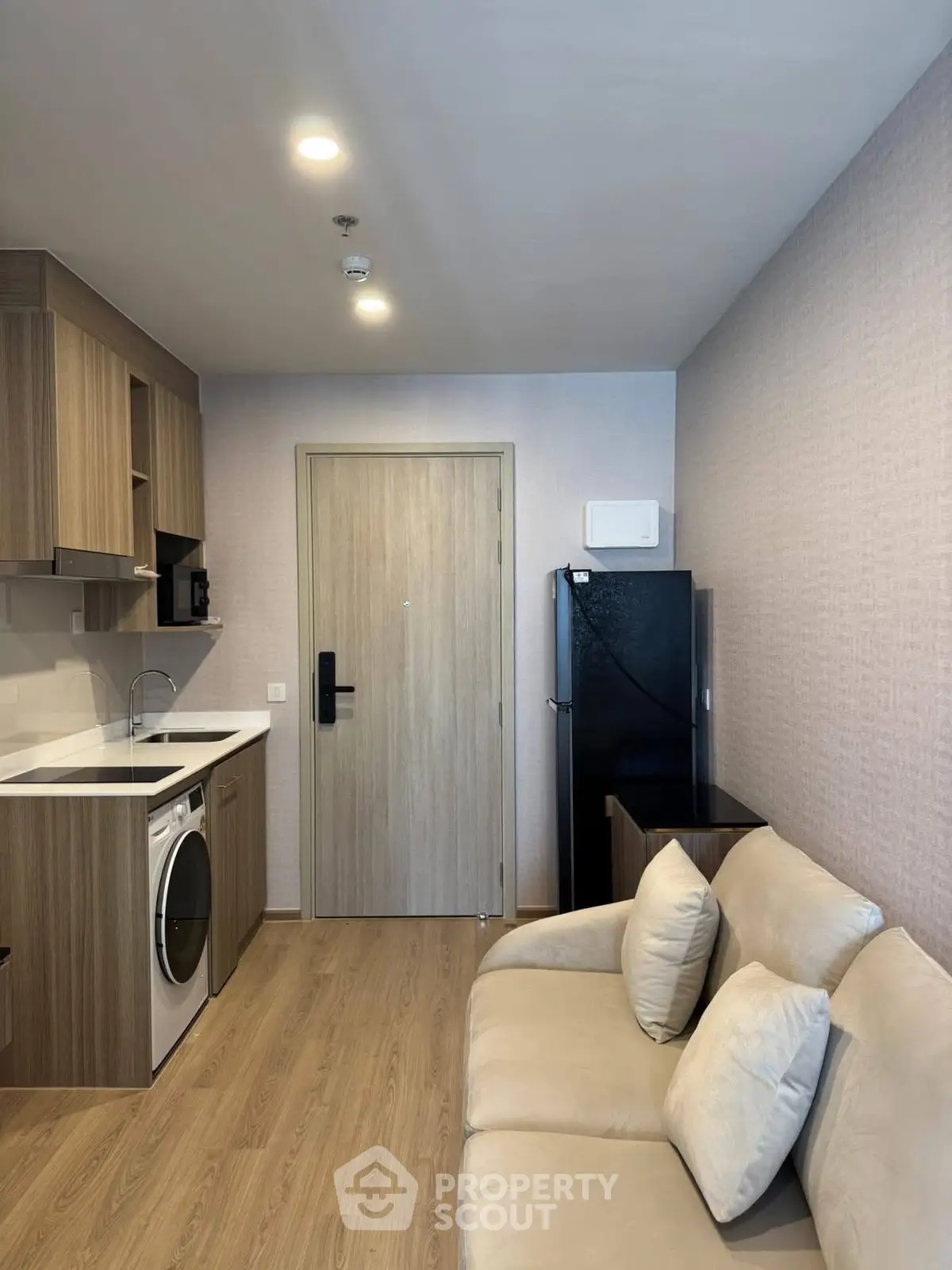 Modern compact apartment with cozy living area and integrated kitchen appliances.