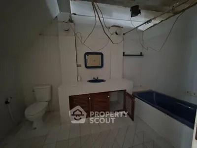 Spacious bathroom with unique blue bathtub and rustic wooden cabinets, ideal for renovation enthusiasts.