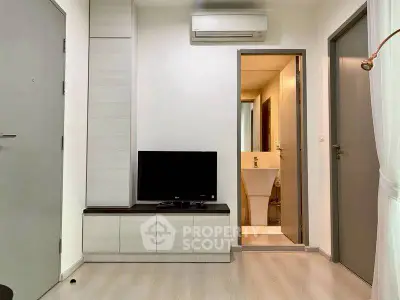 Modern living room with sleek TV unit and view into minimalist bathroom