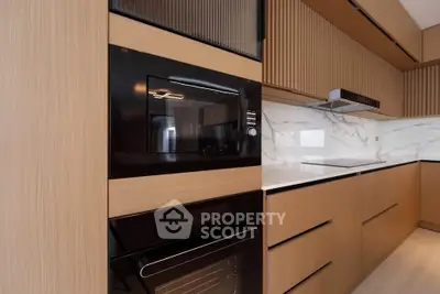 Modern kitchen with sleek wooden cabinetry and built-in oven, featuring a minimalist design and marble backsplash.