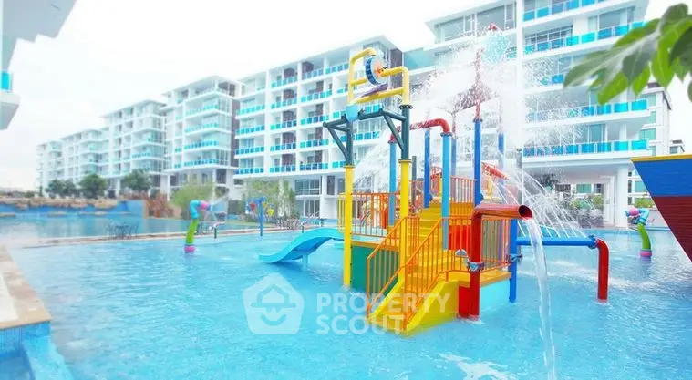 Vibrant family-friendly pool with water slides and play structures at a modern residential complex, showcasing a fun and active community lifestyle.