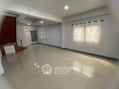 Spacious empty living room with tiled flooring and large windows, perfect for customization.