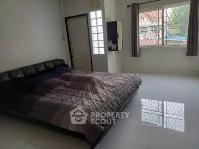Spacious bedroom with large window and modern bed in a bright, airy setting.